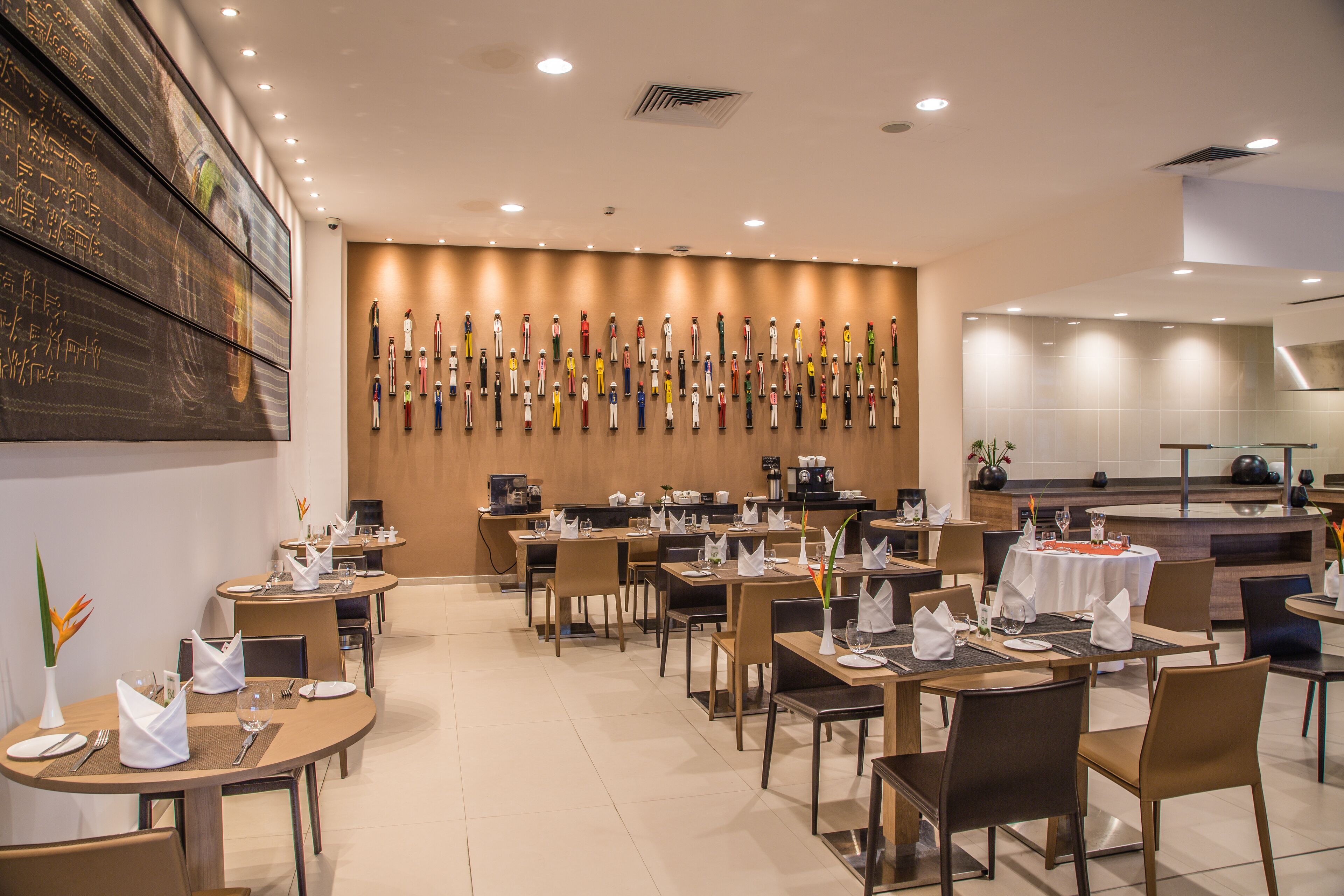 Un restaurante moderno con varias mesas, sillas y una pared decorada con diversos objetos.