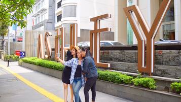 A group of people taking a selfie on a city sidewalk with large 'Y' letters in the background.