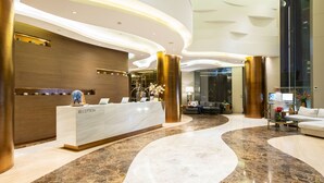 A modern reception area with a marble floor, a reception desk labeled "RECEPTION," and a seating area with a sofa and a coffee table. - Ashley Wahid Hasyim Jakarta (Jakarta)