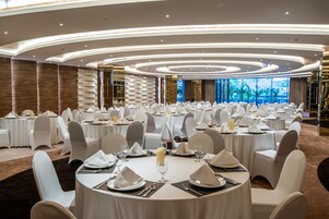 Un salón de banquetes con mesas redondas dispuestas para un evento formal, con manteles blancos, sillas y centros de mesa.