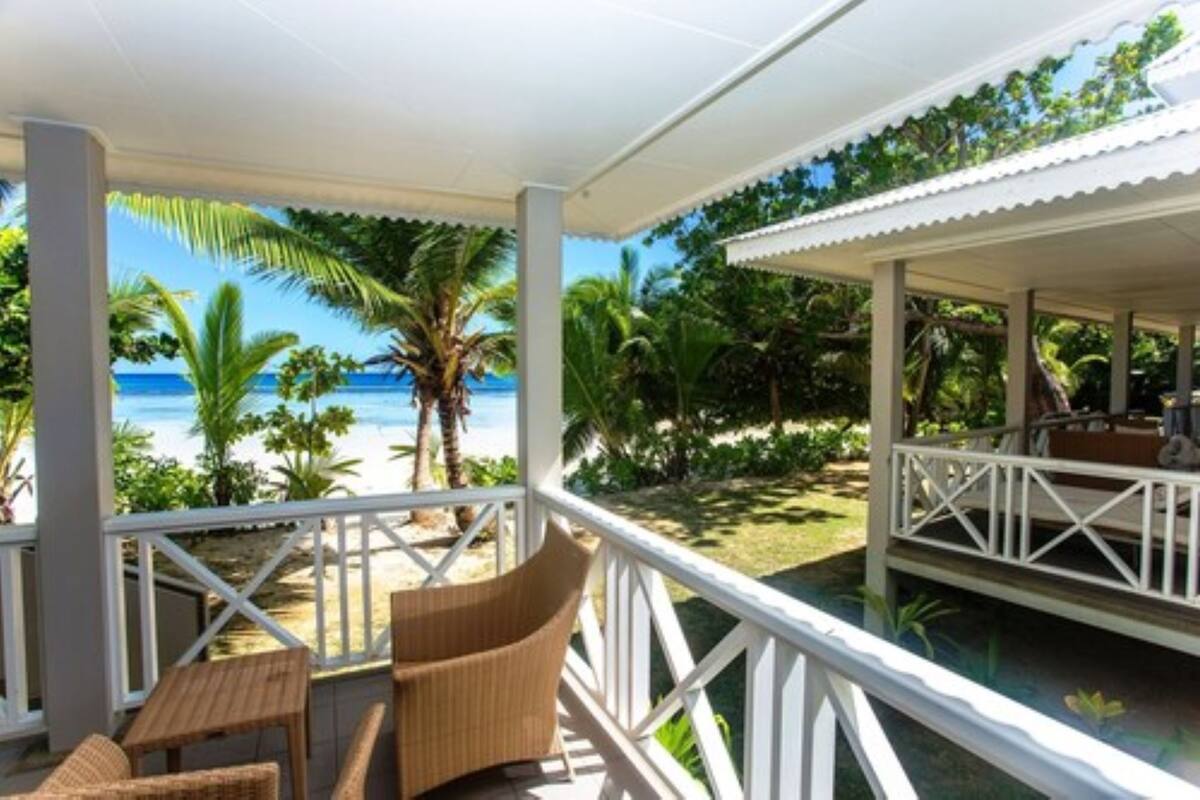 A covered outdoor area with wicker furniture and a view of the beach.