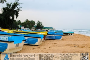 A row of colorful boats on a sandy beach with a hotel sign in the foreground.