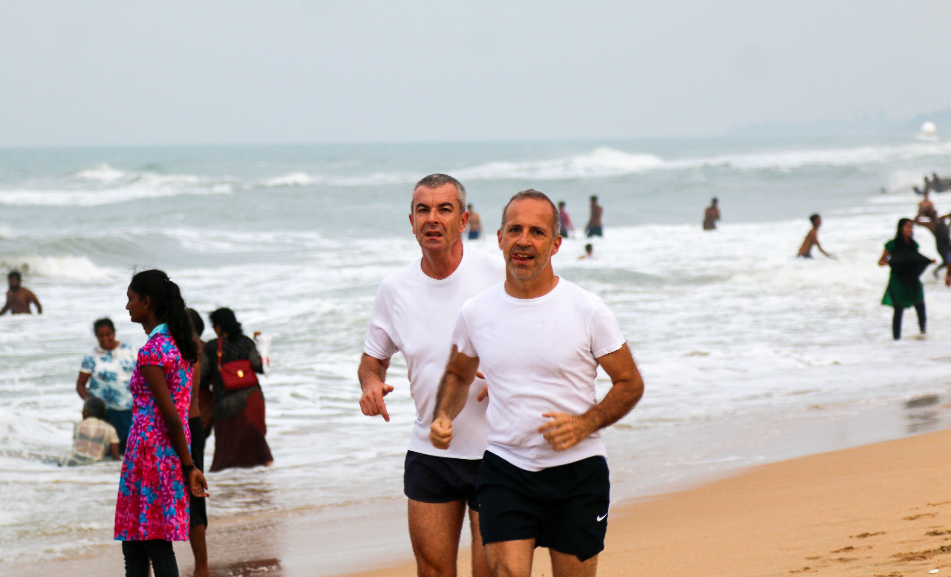 Escena de playa con gente corriendo por la orilla.