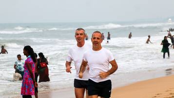 Escena de playa con gente corriendo por la orilla.