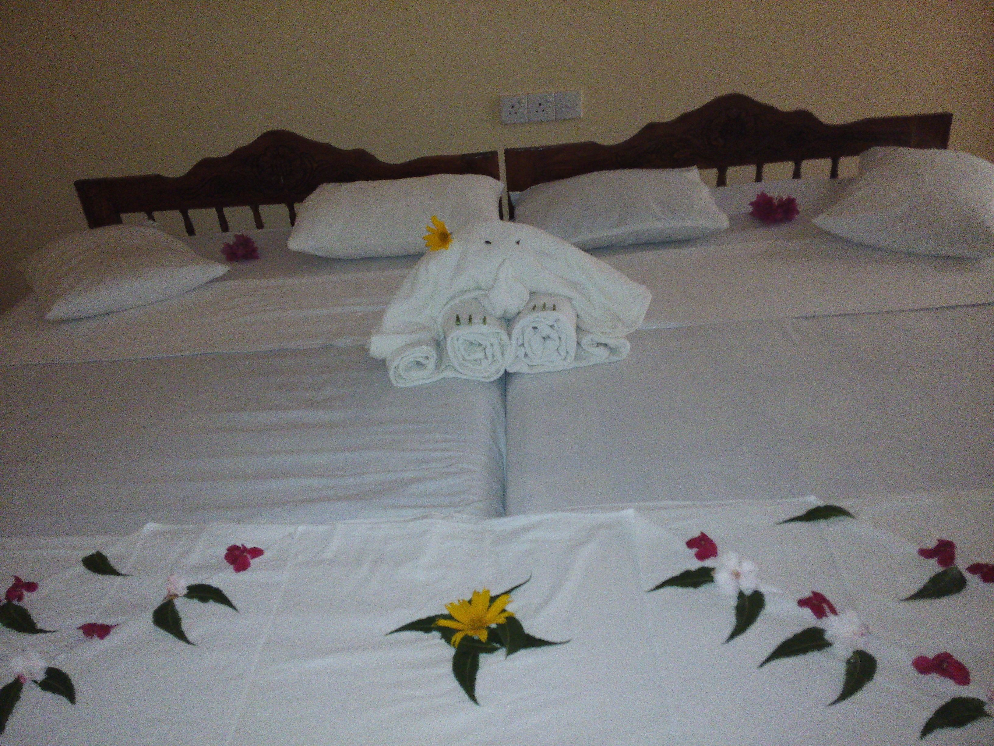 Una cama bien hecha con sábanas blancas y una colcha estampada con motivos florales.