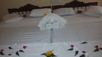 Una cama bien hecha con sábanas blancas y una colcha estampada con motivos florales.