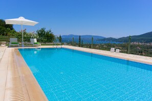 Una piscina al aire libre, sombrillas, tumbonas