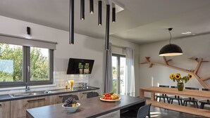 A modern kitchen with a central island, a dining area with a wooden table, and a large window with curtains.