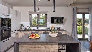 A modern kitchen with a central island, built-in appliances, and a large window.