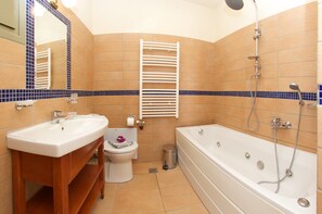Une salle de bain équipée d’un lavabo, de toilettes et d’une baignoire, avec des carreaux bleus et beiges.