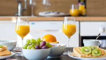 Desayuno con waffles, un bol de uvas y vasos de jugo de naranja.