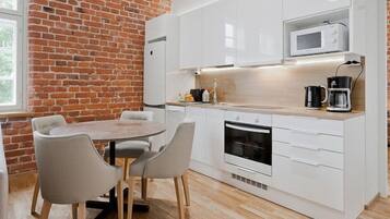 A compact kitchen with white cabinets, a microwave, a coffee maker, and a dining area with a table and chairs.