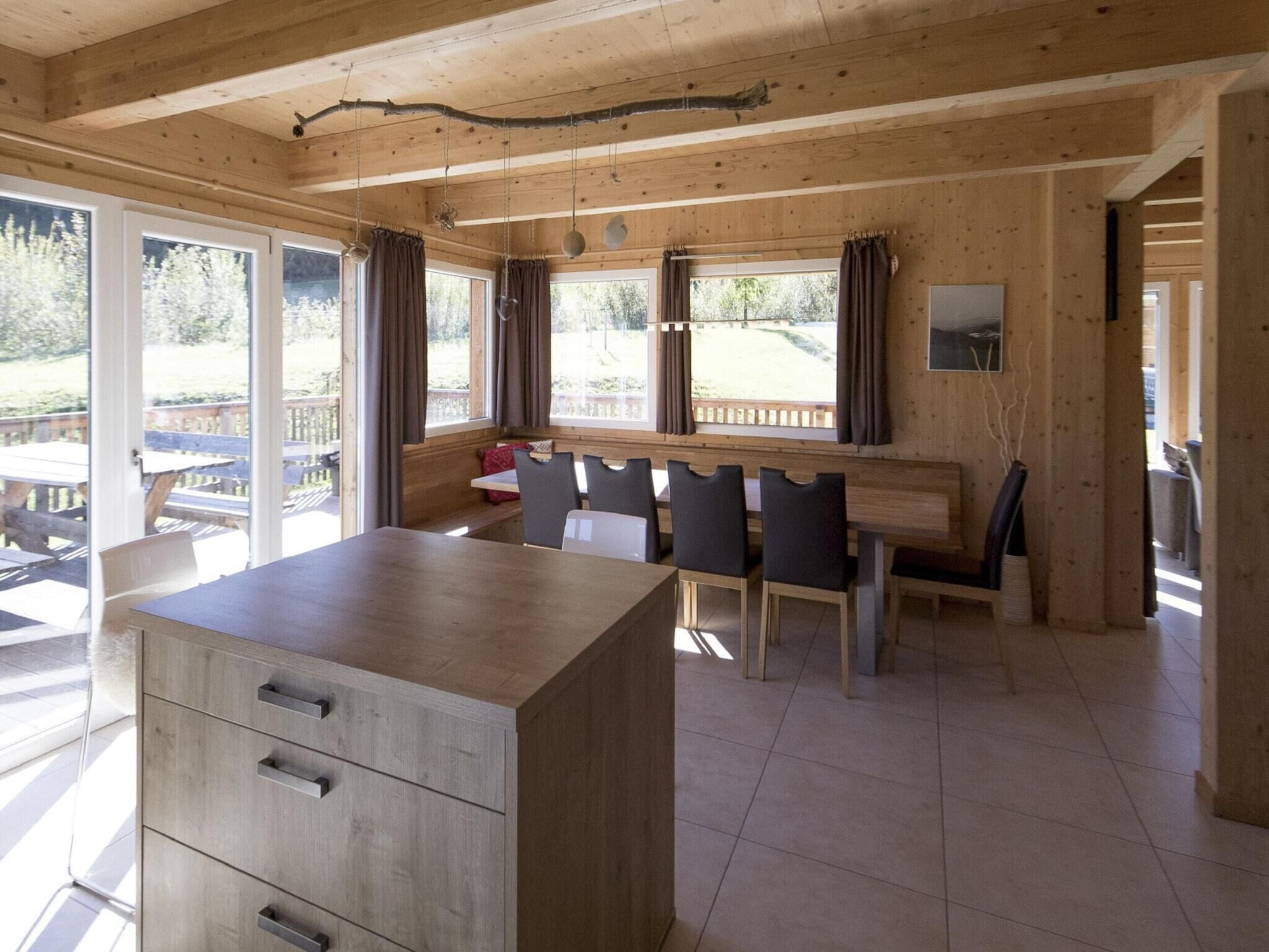Un interior de madera con comedor, ventanas amplias y vistas al exterior.