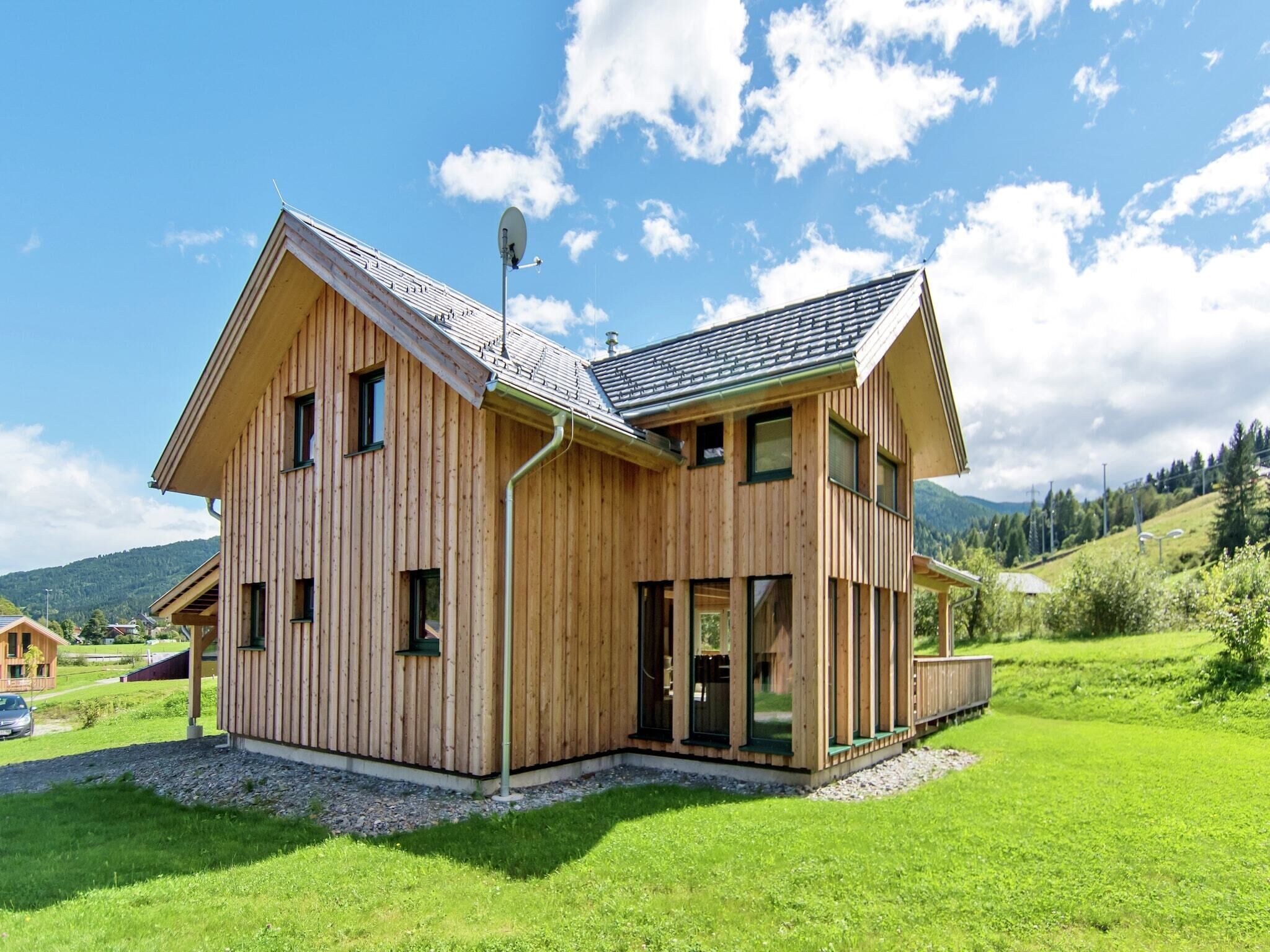 Ett trähus med ett sluttande tak, stora fönster och en satellitmottagare.