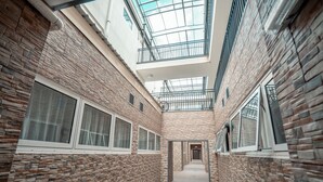 A corridor with brick walls, large windows, and a skylight. - CityLights Hotel (Perth)