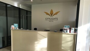 A reception desk at Citylights Hotel with a logo, a welcome mat, and informational brochures. - CityLights Hotel (Perth)