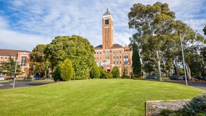 A large building with a prominent tower, surrounded by well-maintained lawns and trees. - Ivy Units Glen Waverley (Glen Waverley)