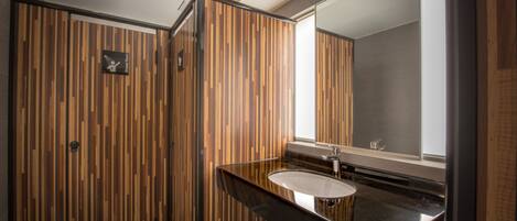 Un baño moderno con pared de paneles de madera, encimera negra y un espejo grande.