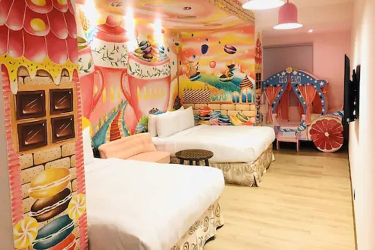 A room with two white sofas, a colorful mural, a carousel, and a wall with a pattern of stacked objects.