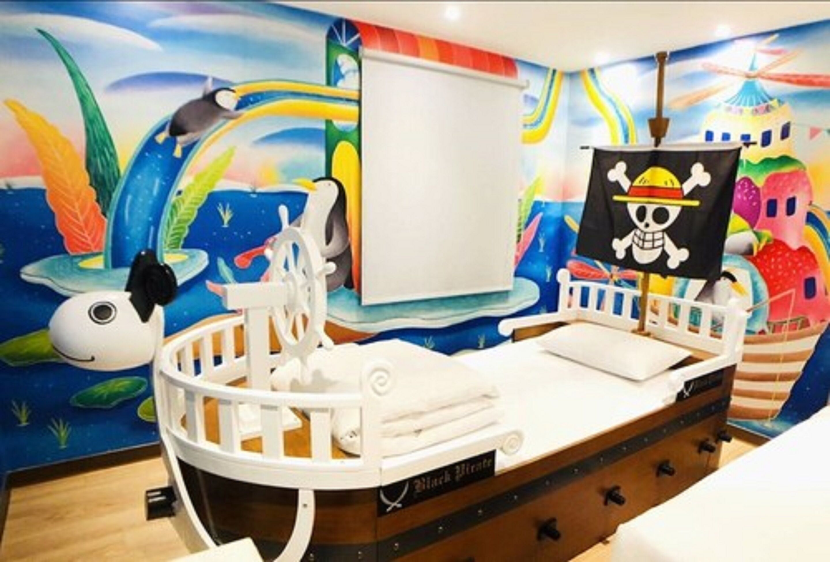 A child's room with a bed shaped like a pirate ship, a mural with sea creatures, and a skull and crossbones flag.