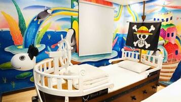 A child's room with a bed shaped like a pirate ship, a mural with sea creatures, and a skull and crossbones flag.