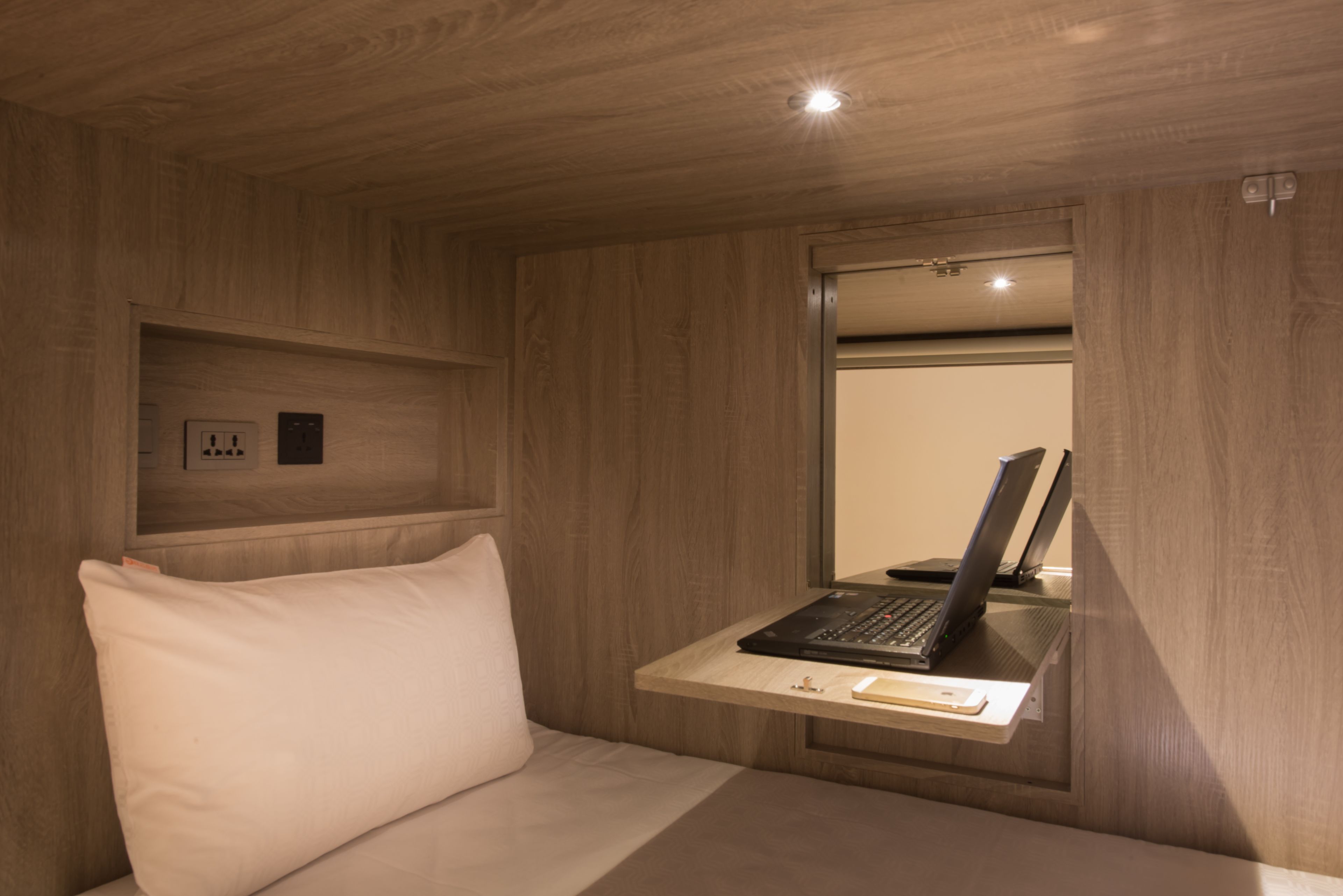 A room with a bed, a desk with a laptop, and a mirror.