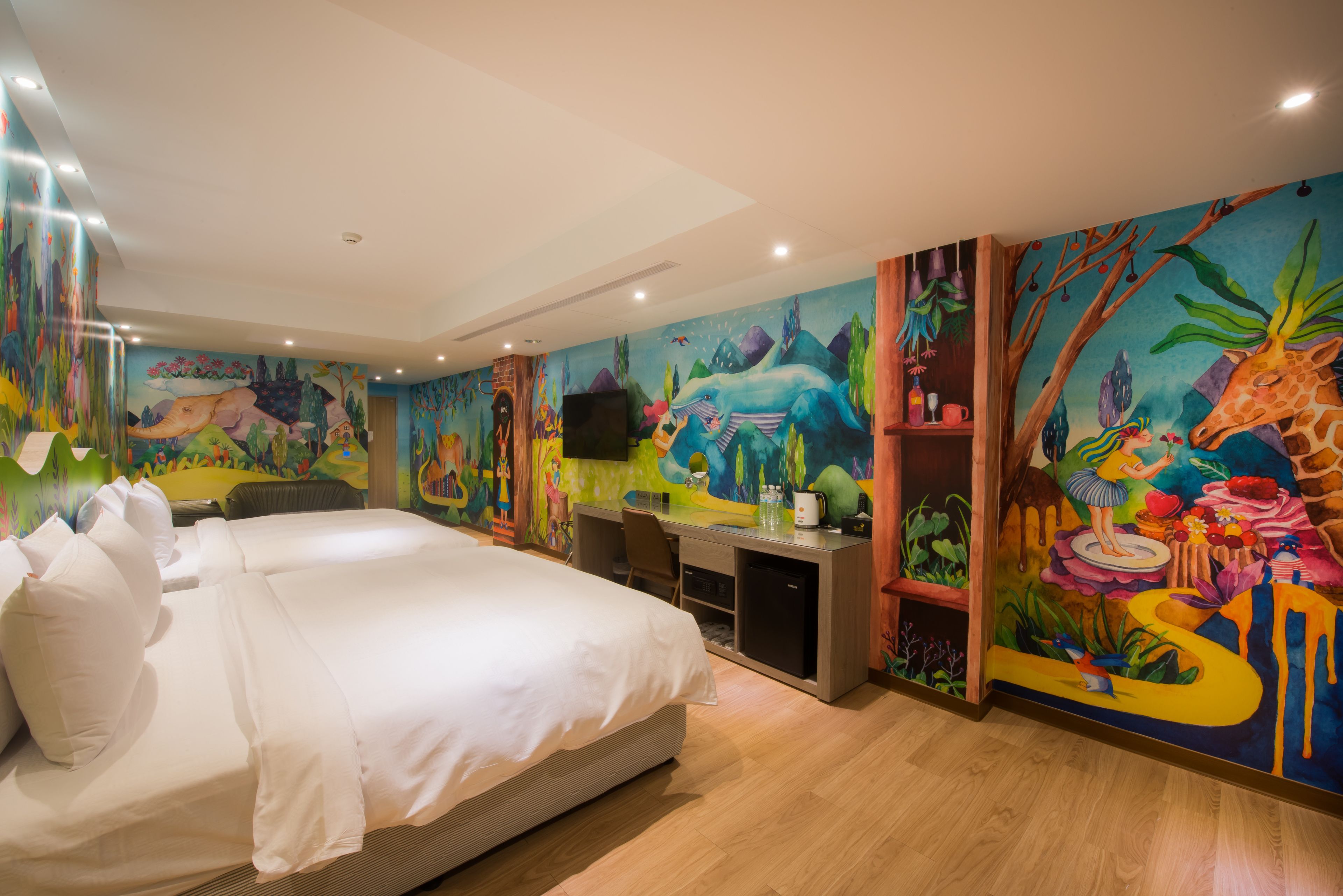 Une chambre d’hôtel avec un grand lit, un bureau et une fresque colorée sur les murs.