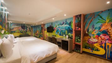 Quarto de hotel com uma cama grande, uma escrivaninha e um mural colorido nas paredes.