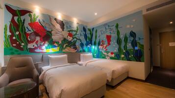 A hotel room with two beds, a chair, a small table, and a mural of fish and seaweed on the wall.