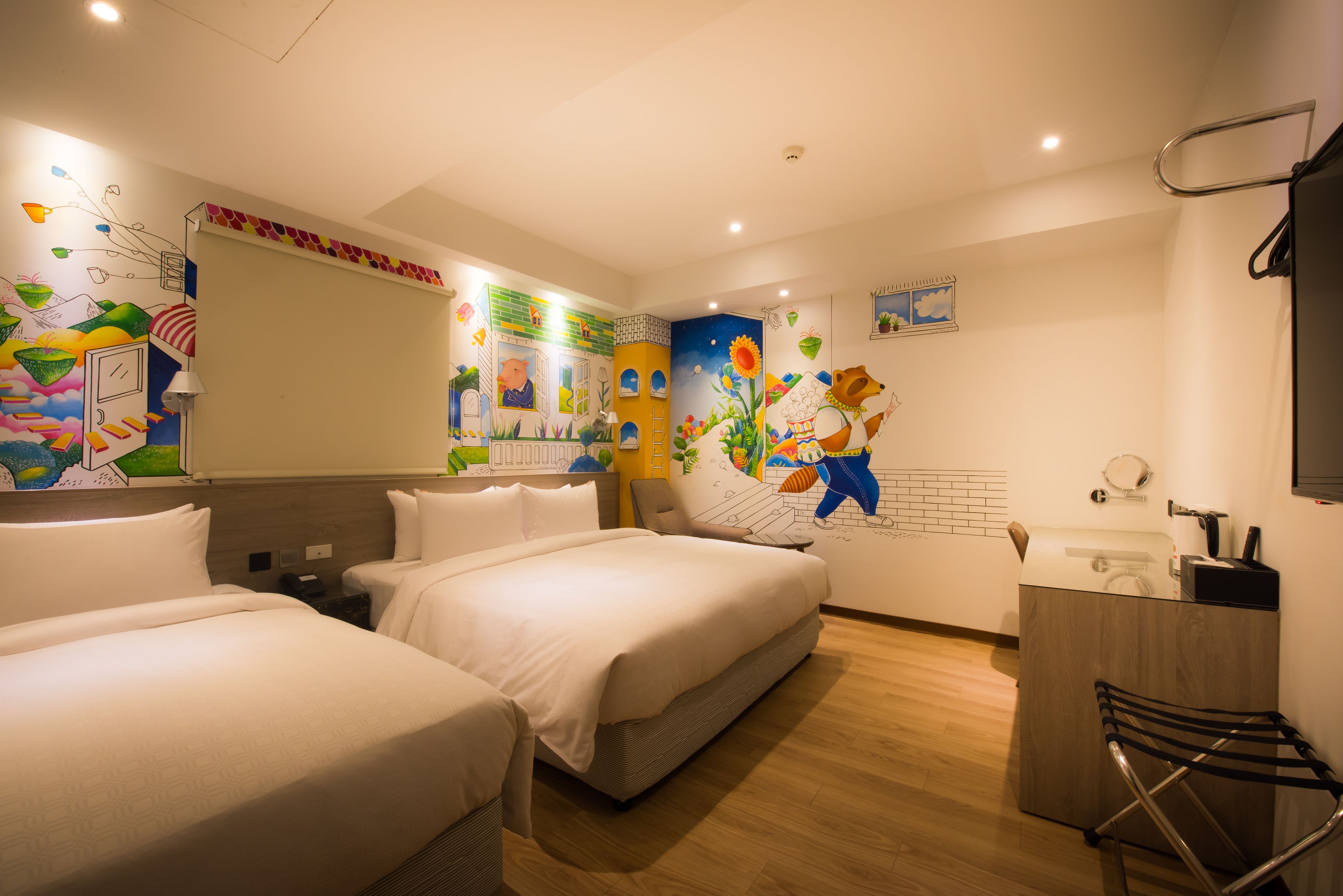 A hotel room with two beds, a desk, and a bathroom.