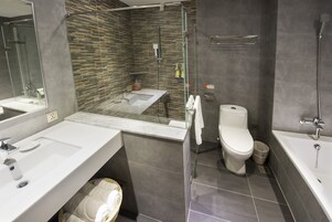 Un bagno moderno con doccia vetro, lavandino separato e water.