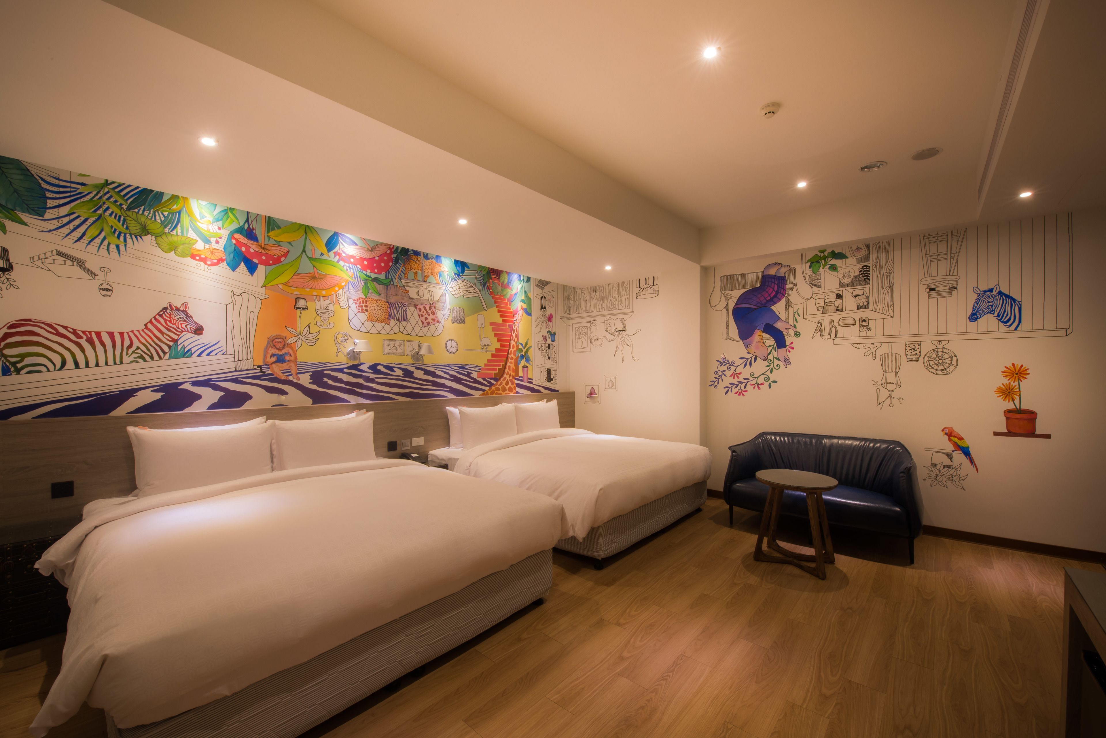 A hotel room with two beds, a sofa, and a mural with animal drawings.