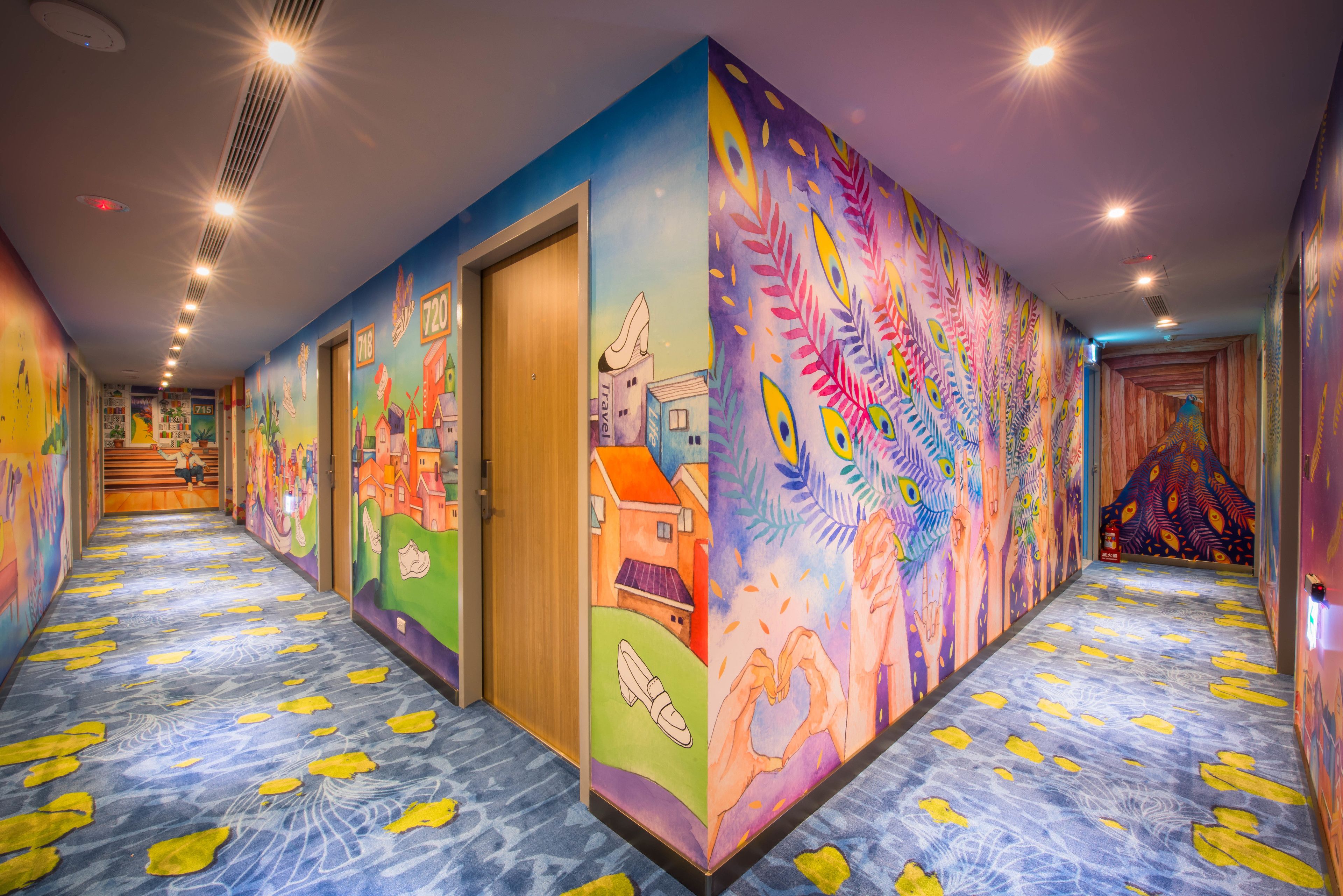 A brightly lit hallway with colorful murals on the walls and a patterned carpet.