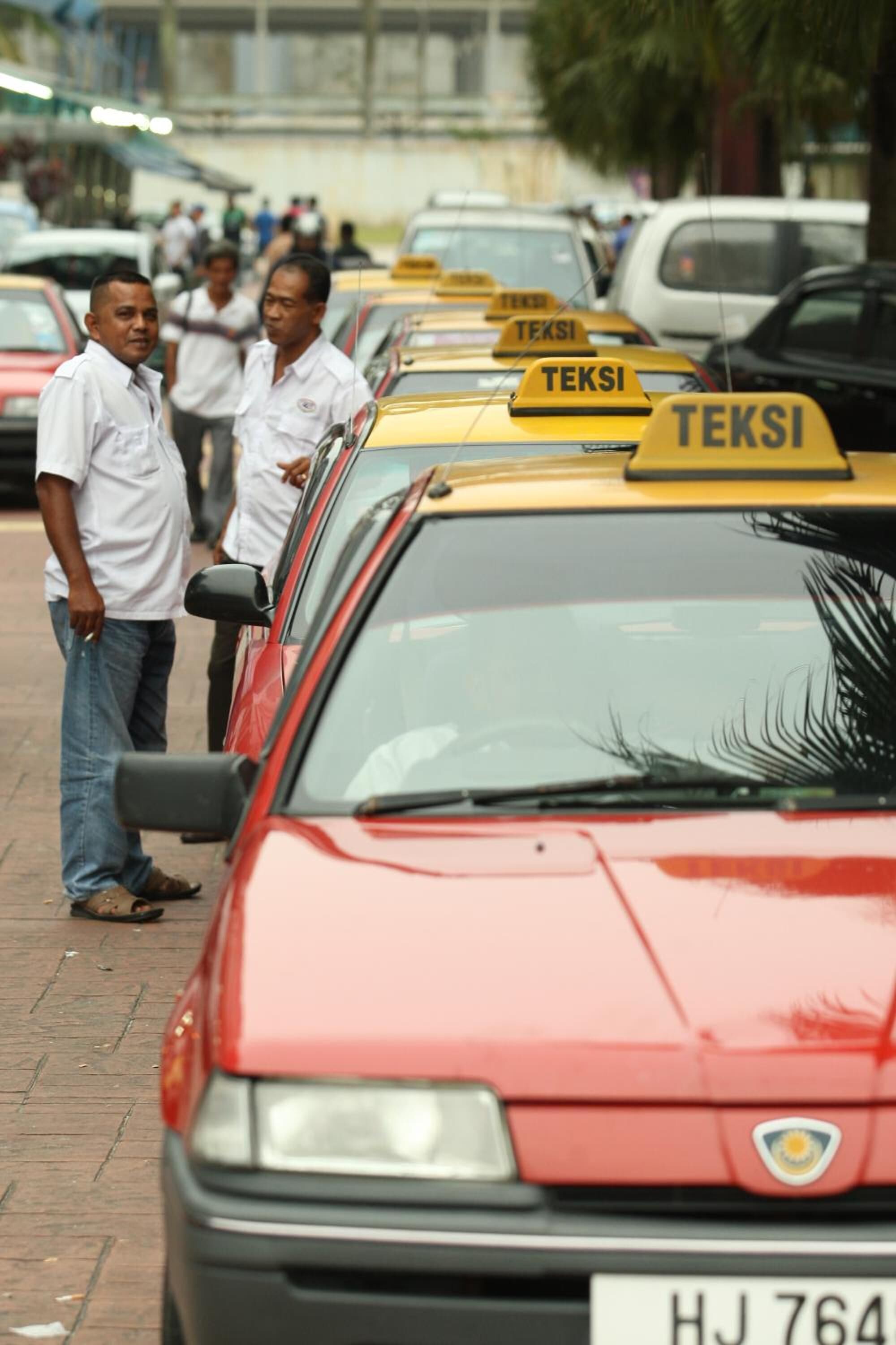A row of yellow taxis with 'TEKSI' signs, parked on a street.