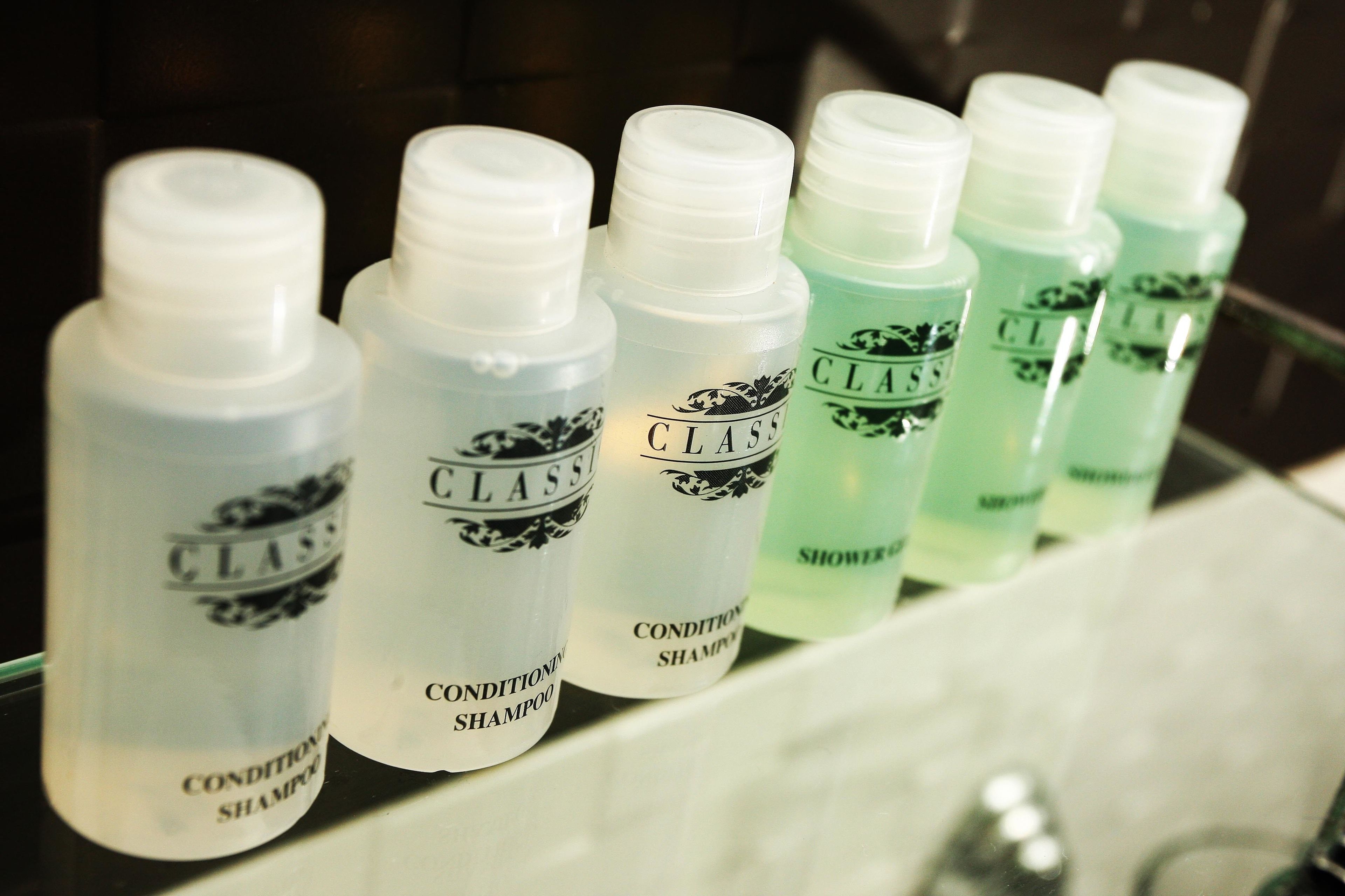 Varias botellas de champú CLASS alineadas en un estante de baño.