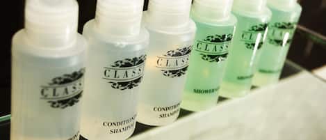 Varias botellas de champú CLASS alineadas en un estante de baño.