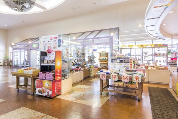Un mercado interior amplio con varios puestos que venden comida y productos, con un pasillo central y un techo con una bola de discoteca.