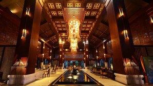 A spacious lobby with a central water feature, wooden paneling, and traditional decor. - Shixishu Jianguo Yalong Bay Resort Hotel (Sanya)