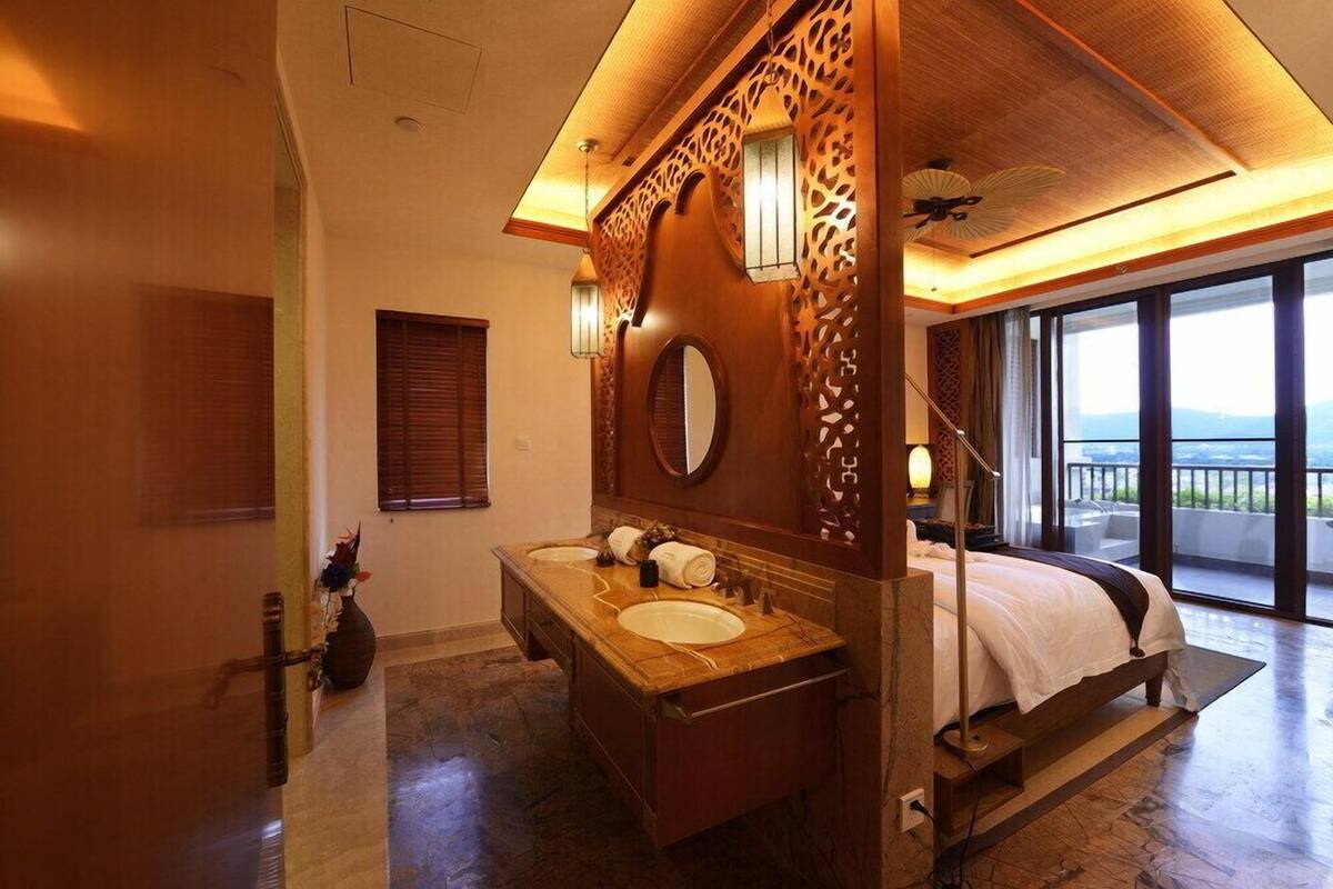 Une salle de bain spacieuse avec un grand meuble-lavabo, un double évier, un miroir et un lit donnant sur un balcon.