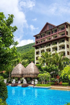 A hotel with a pool area, thatched-roof structures, and lush greenery. - Shixishu Jianguo Yalong Bay Resort Hotel (Sanya)