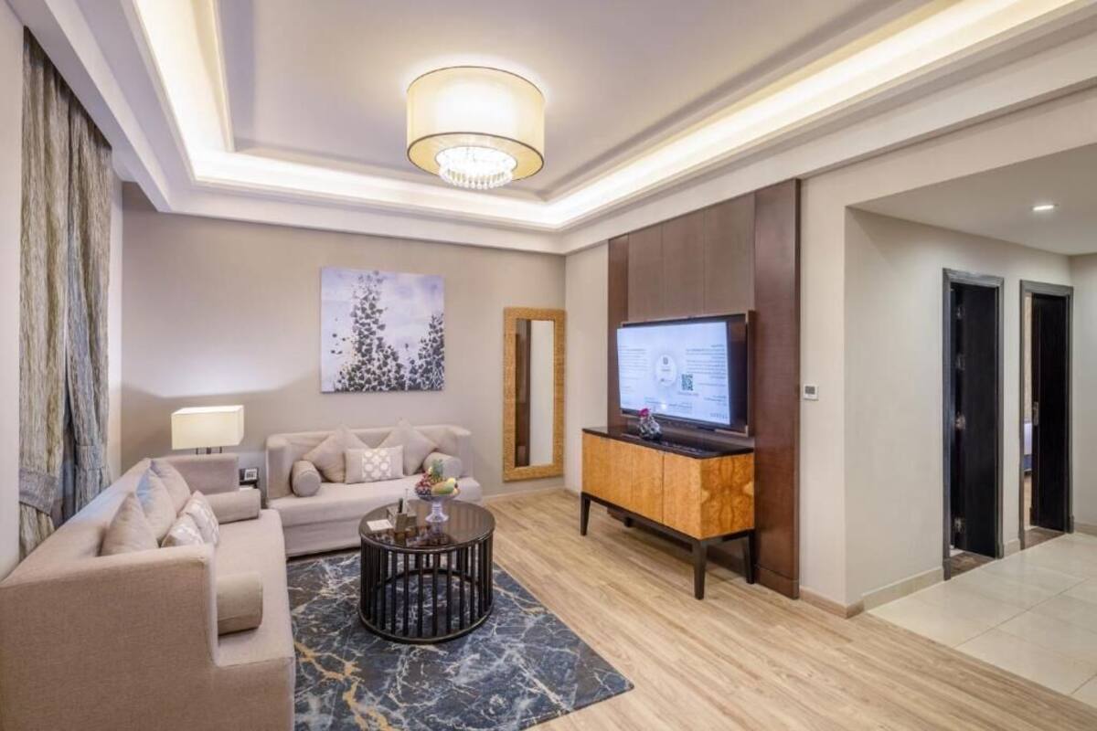 A modern living room with a sofa, coffee table, TV, and a chandelier.