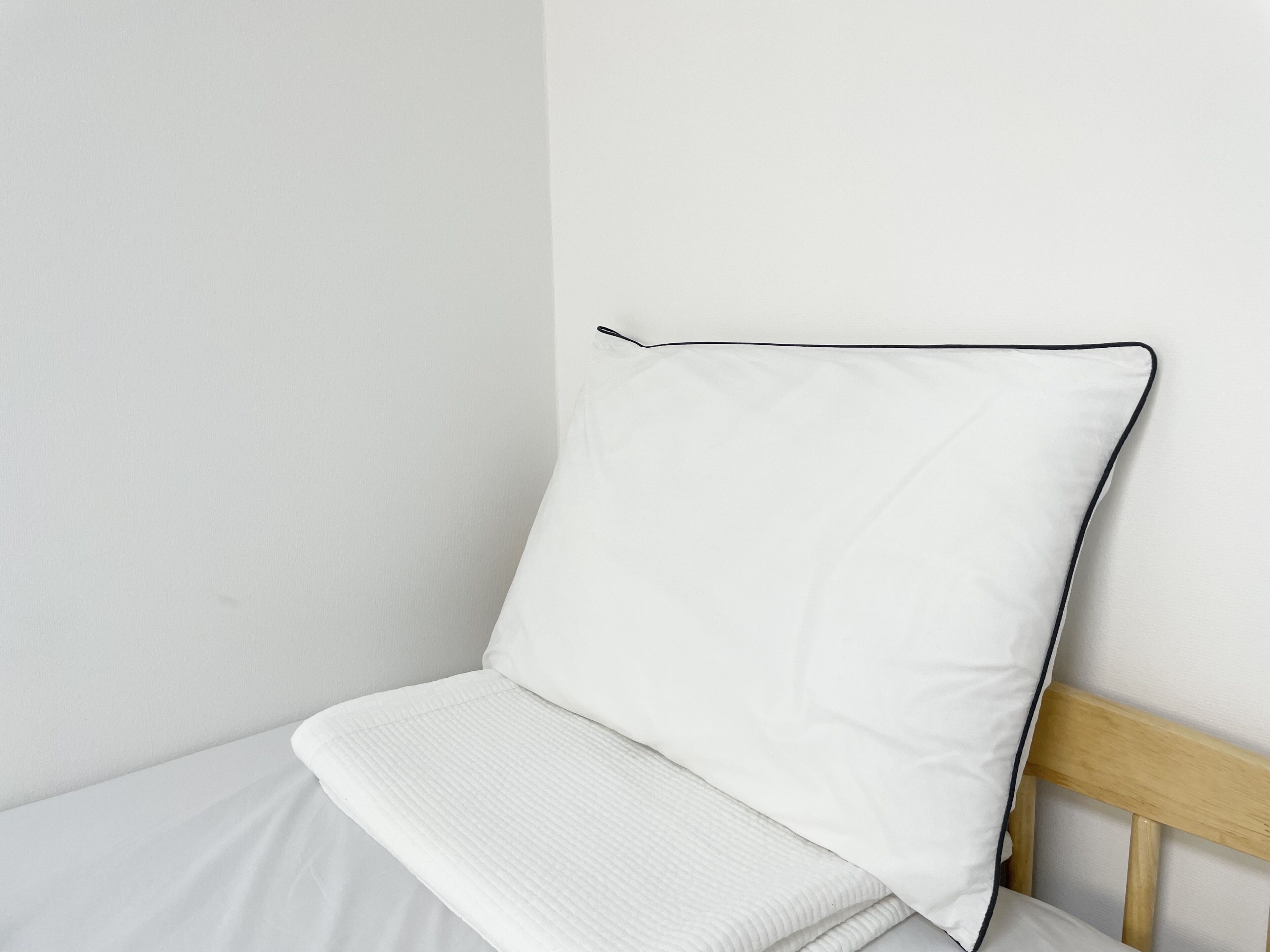 A single bed with a wooden headboard and white bedding.
