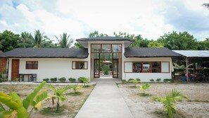 A two-story building with a central entrance, surrounded by a garden with small plants and a paved walkway. - La Playa Estrella Beach Resort (Santa Fe)