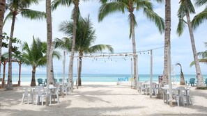 A beach venue with a covered seating area, white plastic chairs, and a view of the ocean. - La Playa Estrella Beach Resort (Santa Fe)