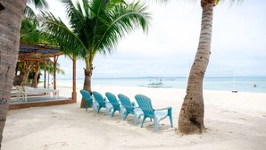 Une plage de sable blanc, une rangée de chaises bleues et des palmiers.