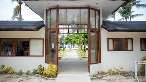 Un bâtiment avec une entrée en verre, un panneau indiquant « INTERDICTION DE STATIONNER » et un chemin menant à une plage.