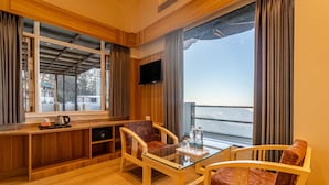 A modern room with wooden furniture, a glass table, and a view of the outdoors. - Treebo Varuna with Mountain View, Mall Road (Shimla)