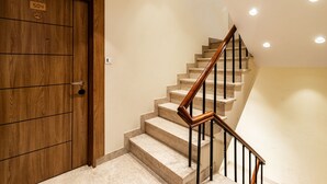 A wooden door with a sign, a marble staircase with wooden handrails, and recessed ceiling lights. - Treebo Varuna with Mountain View, Mall Road (Shimla)