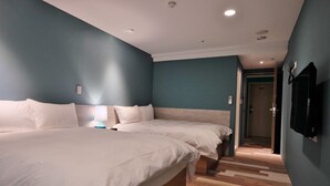 Une chambre d’hôtel moderne avec deux lits, un plancher en bois et un mur d’accent bleu.