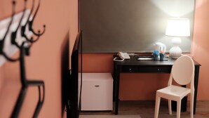 Une chambre d’hôtel équipée d’un bureau, d’une chaise, d’une lampe et d’un petit réfrigérateur blanc.
